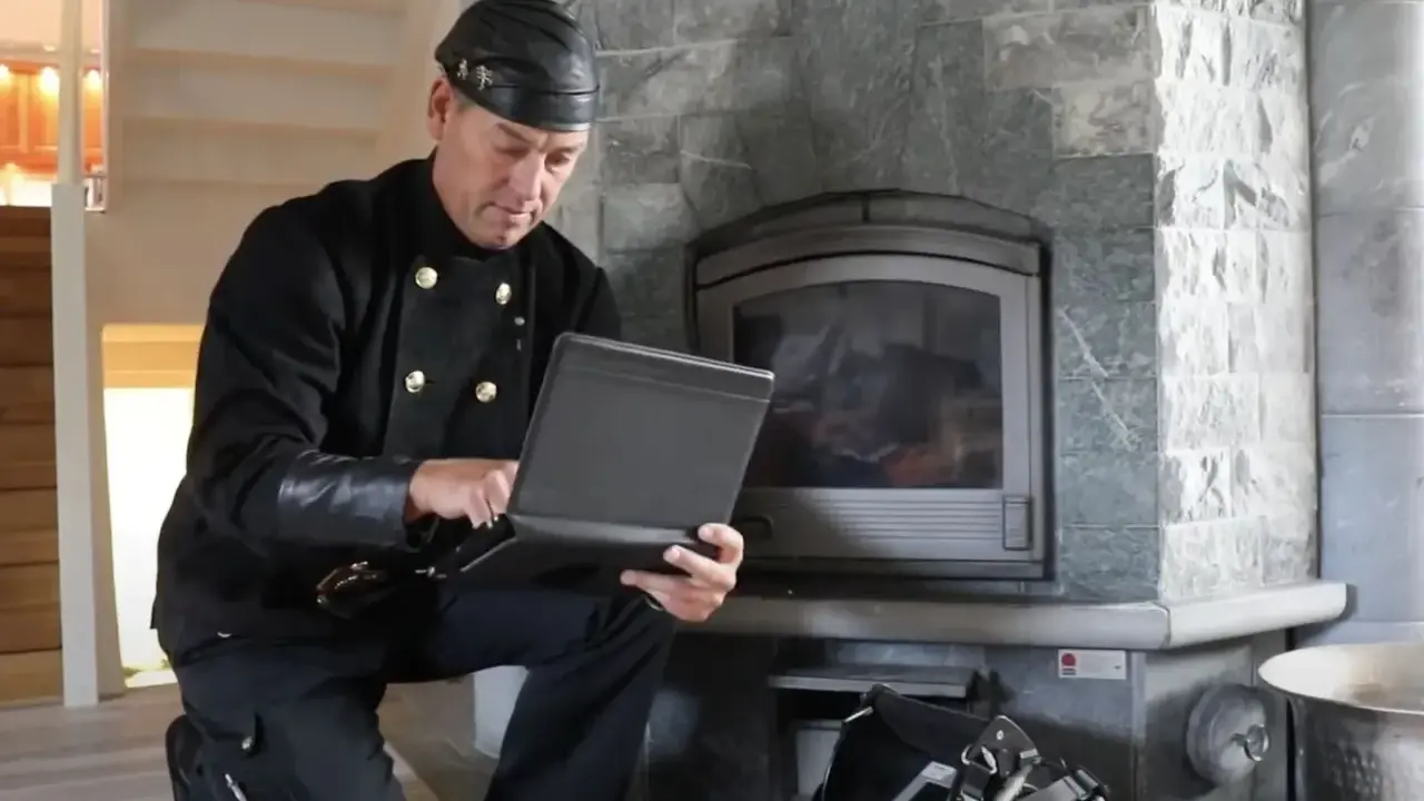 Sotare med laptop vid eldstad. Regelbunden brandskyddskontroll hur ofta är viktig för säkerheten.