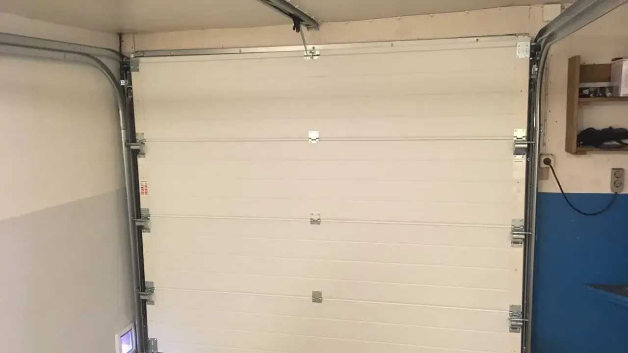 Monteringen av en Verisure magnetkontakt på en vit garageport.