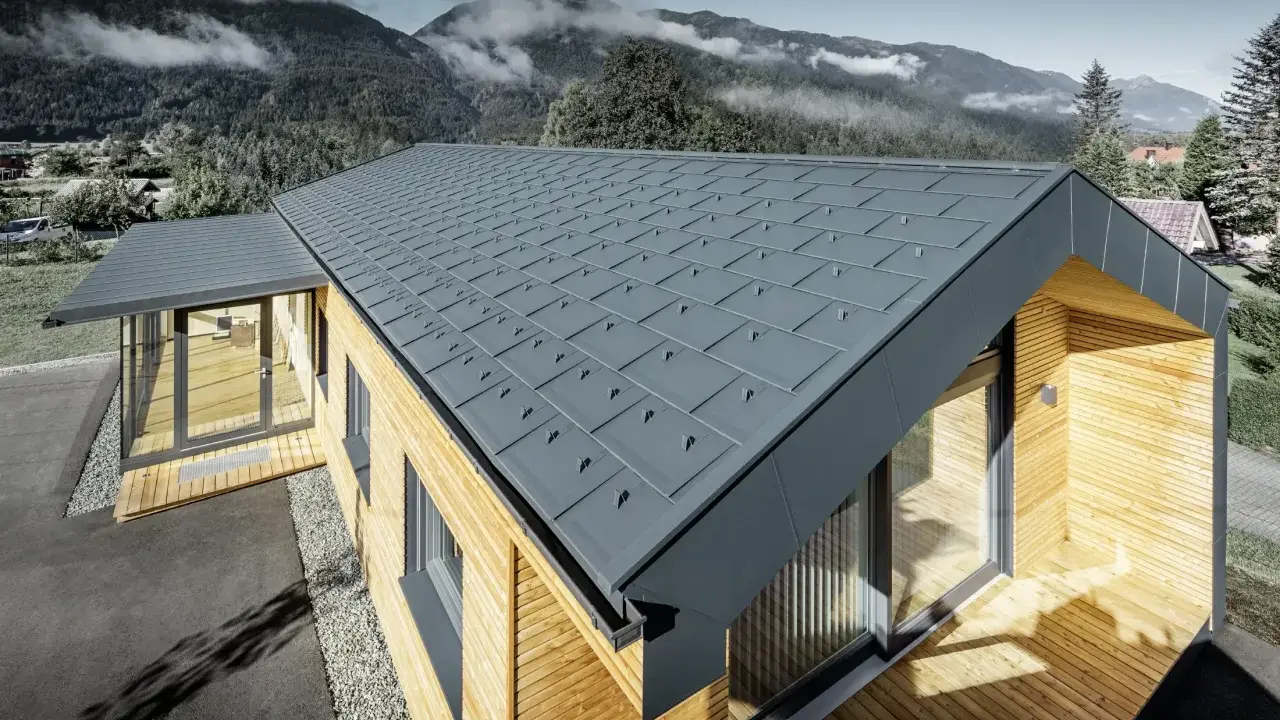Modernt hus med grått plåttak, där åskledare diskret integrerats. Omgivet av berg och skog.