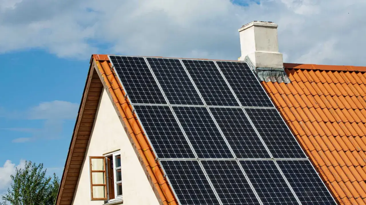 Solceller på ett tegeltak. En öppen fönsterlucka syns på husets gavel. Vissa oroar sig för solceller brandrisk.