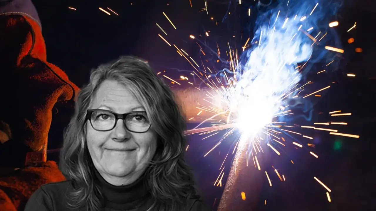 Kvinna med glasögon ler framför en bakgrund av gnistor från heta arbeten. En svetsare i skyddskläder syns till vänster.