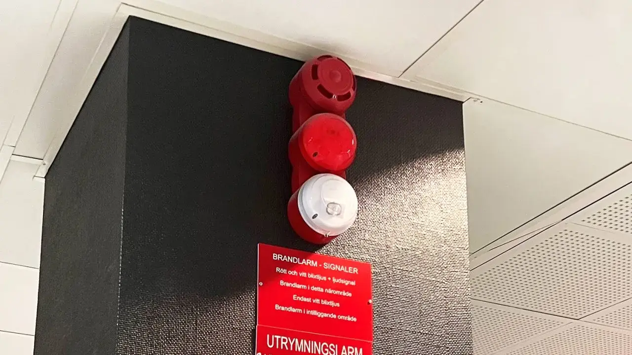 Rött och vitt larmdon brandlarm med textskylt. En varningssignal för utrymning.
