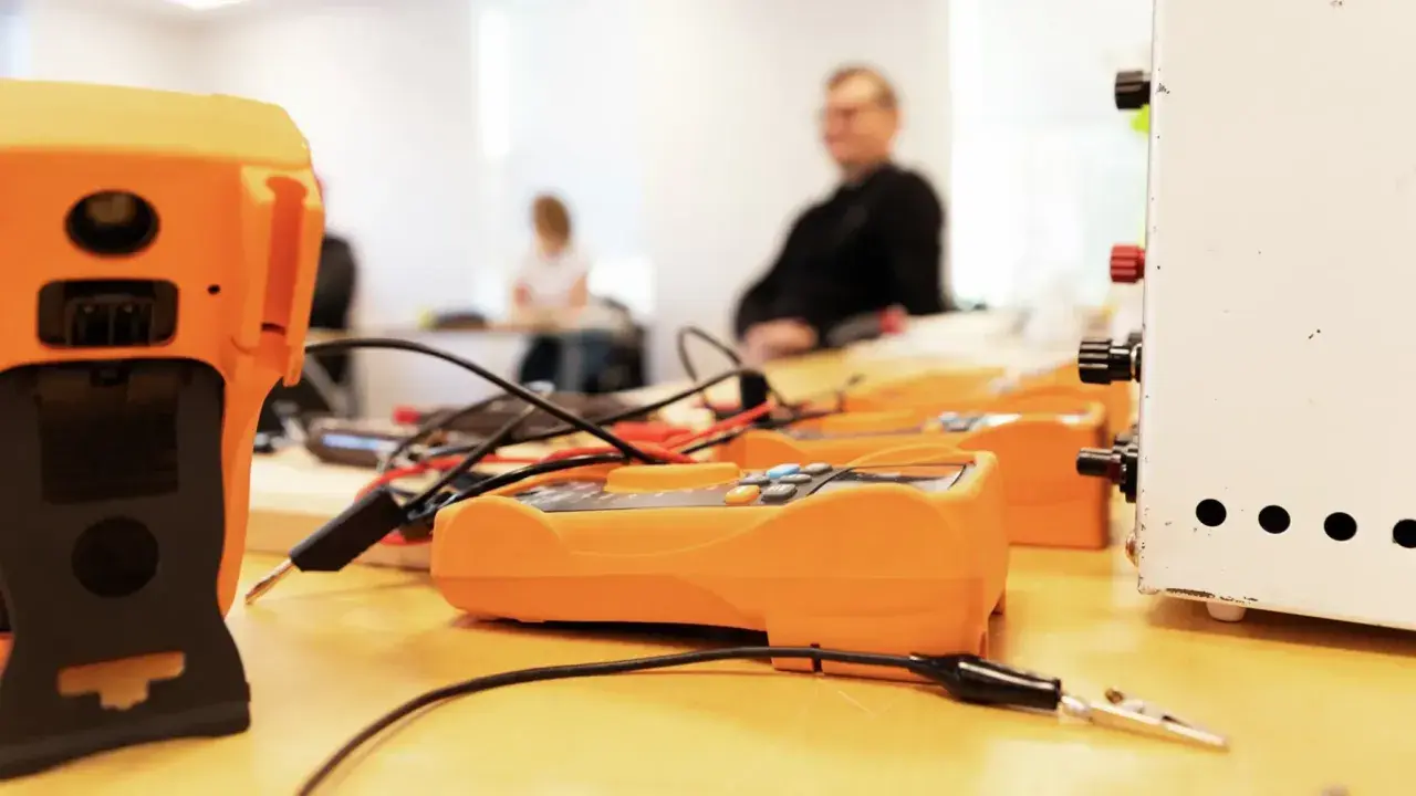 Orange multimeters och en vit apparat på ett bord, redo för pyroteknik utbildning.
