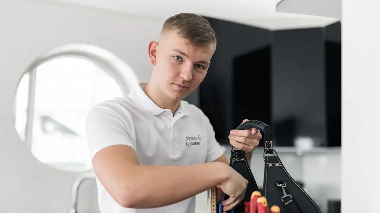 En ung elektriker från Svenska Eljouren tar fram verktyg ur sin väska för en snabb elinstallation.