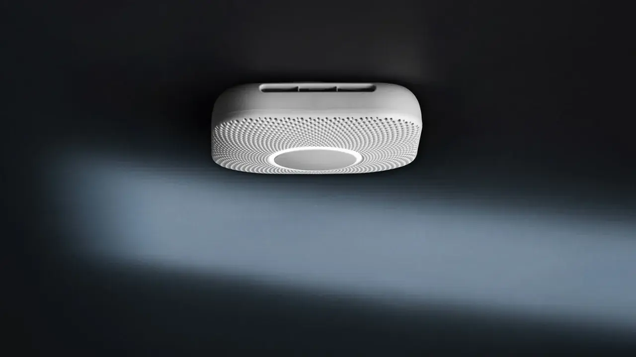 En vit Google Nest Protect-rökdetektor med en cirkulär ljusring monterad i taket.