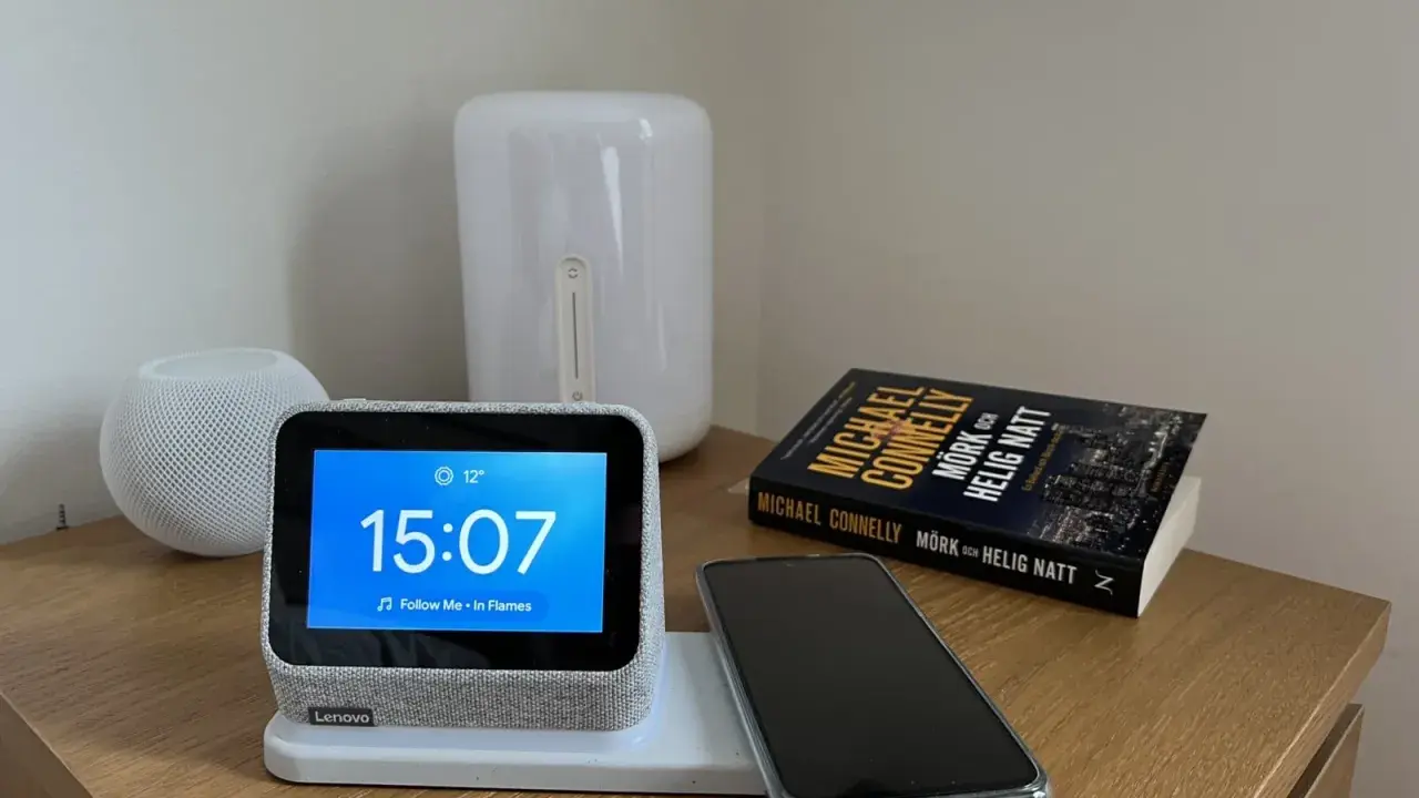 En smartklocka visar 15:07, en mobil ligger redo att ladda mobilen på natten bredvid en bok.