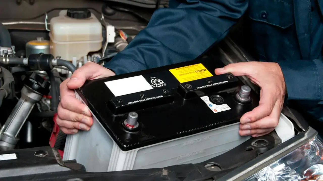 Mekaniker byter bilbatteri. Undvik kortslutning bilbatteri genom att hantera det varsamt.
