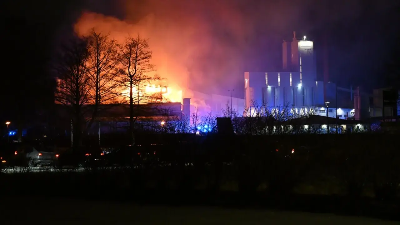 En fabrik brinner med orange och lila rök. Kanske en påminnelse om vikten av att följa kurs Boverkets brandregler för att undvika sådana katastrofer.