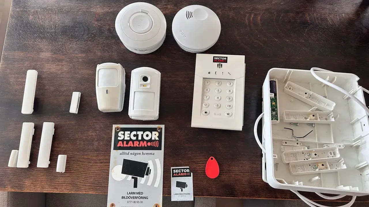 Säkerhetssystem från Sector Alarm, inklusive larmpanel, rörelsedetektorer, dörrsensorer och en tom larmcentral. Perfekt för en trygg home assistant.
