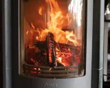 En eldstad med flammande ved. Trots det dåliga draget i kaminen lyser elden starkt och skapar en mysig atmosfär.