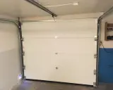 Monteringen av en Verisure magnetkontakt på en vit garageport.