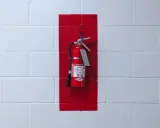 Brandskydd garage: Röd brandsläckare hänger på en vit tegelvägg, markerad med en röd rektangel.