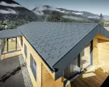 Modernt hus med grått plåttak, där åskledare diskret integrerats. Omgivet av berg och skog.