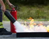 Person i skyddskläder släcker eld med brandsläckare. Praktisk brand utbildning för säkerhet.