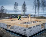 Byggnadsarbetare arbetar med grunden till ett hus, i enlighet med plan- och bygglagen. En maskin står i bakgrunden.