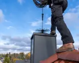 Sotare på taket med verktyg för sotning. En brandskyddskontroll pris kan variera beroende på skorstenens skick.