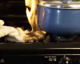 En gryta står på spisen med en handduk som börjar brinna. En påminnelse om att vara försiktig, en **stanley brandlarm** kan vara bra att ha.