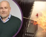 Man med skägg och en brandhärjad trappa med brandsläckare. Viktigt med revisionsbesiktning brandlarm för säkerheten.