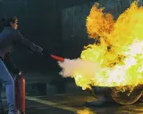 Övning i brandutbildning på jobbet. En person släcker en stor eld med en brandsläckare.