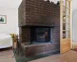 En murad spis med sotfläckar som behöver rengöras. Bredvid står en säng och en dörr.