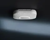 En vit Google Nest Protect-rökdetektor med en cirkulär ljusring monterad i taket.