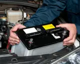 Mekaniker byter bilbatteri. Undvik kortslutning bilbatteri genom att hantera det varsamt.