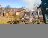 Två personer eldar trädgårdsavfall. Röken stiger mot en klarblå himmel.