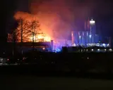 En fabrik brinner med orange och lila rök. Kanske en påminnelse om vikten av att följa kurs Boverkets brandregler för att undvika sådana katastrofer.