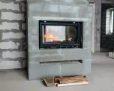 En nyinstallerad kamin med eld i, omgiven av byggmaterial. Snart blir det varmt och mysigt!