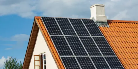 Solceller på ett tegeltak. En öppen fönsterlucka syns på husets gavel. Vissa oroar sig för solceller brandrisk.
