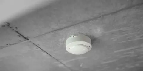 En vit brandvarnare monterad i ett betongtak. Denna enhet är avgörande för att veta hur lång tid står en brandcell oftast emot brand.