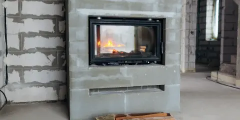 En nyinstallerad kamin med eld i, omgiven av byggmaterial. Snart blir det varmt och mysigt!