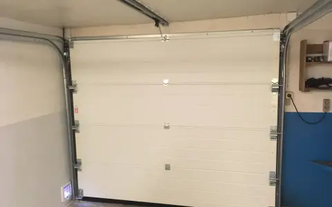 Monteringen av en Verisure magnetkontakt på en vit garageport.