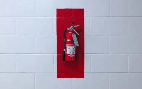 Brandskydd garage: Röd brandsläckare hänger på en vit tegelvägg, markerad med en röd rektangel.