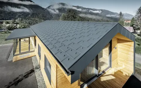 Modernt hus med grått plåttak, där åskledare diskret integrerats. Omgivet av berg och skog.