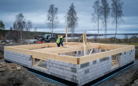 Byggnadsarbetare arbetar med grunden till ett hus, i enlighet med plan- och bygglagen. En maskin står i bakgrunden.
