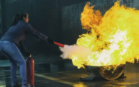 Övning i brandutbildning på jobbet. En person släcker en stor eld med en brandsläckare.