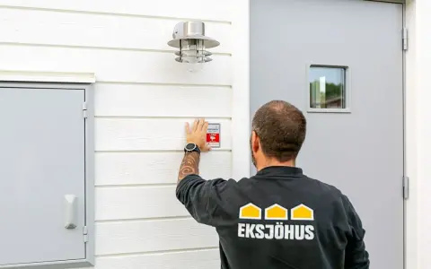 Man monterar en Verisure-larmdekal på husfasaden, en del av ett smart hem-system som kan integreras med Google Home.