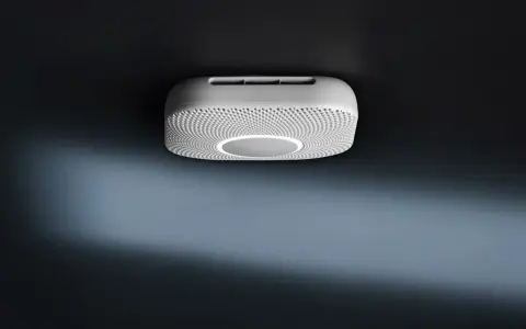 En vit Google Nest Protect-rökdetektor med en cirkulär ljusring monterad i taket.