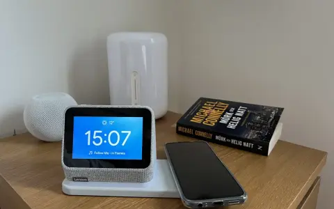 En smartklocka visar 15:07, en mobil ligger redo att ladda mobilen på natten bredvid en bok.