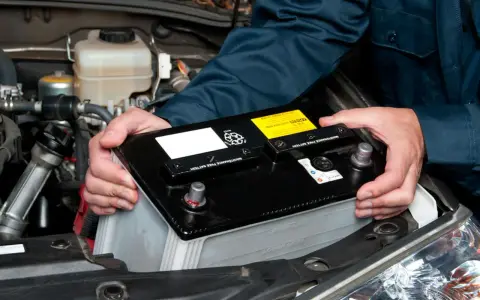 Mekaniker byter bilbatteri. Undvik kortslutning bilbatteri genom att hantera det varsamt.