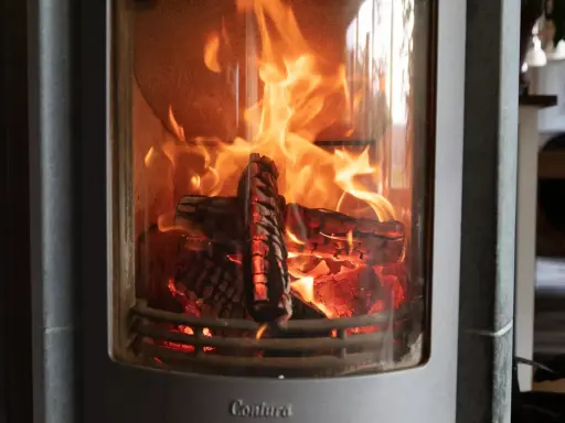 En eldstad med flammande ved. Trots det dåliga draget i kaminen lyser elden starkt och skapar en mysig atmosfär.