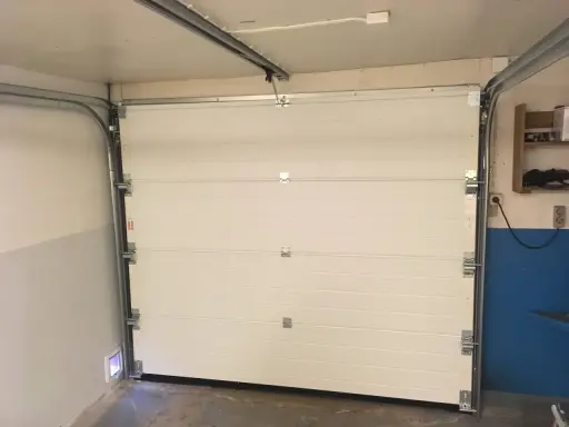 Monteringen av en Verisure magnetkontakt på en vit garageport.