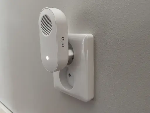 Arlo doorbell-installation: en vit Arlo-enhet med en lysande prick är ansluten till ett vägguttag.