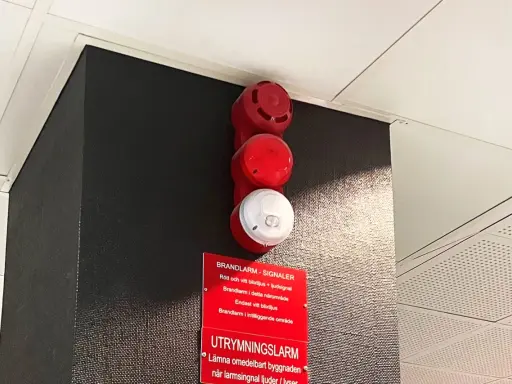 Rött och vitt larmdon brandlarm med textskylt. En varningssignal för utrymning.