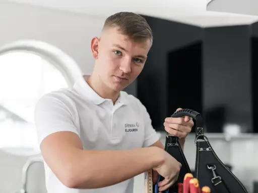 En ung elektriker från Svenska Eljouren tar fram verktyg ur sin väska för en snabb elinstallation.