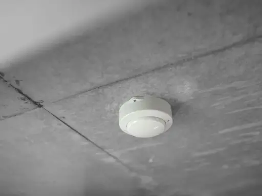 En vit brandvarnare monterad i ett betongtak. Denna enhet är avgörande för att veta hur lång tid står en brandcell oftast emot brand.