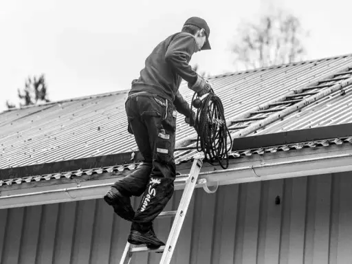 Sotare klättrar på taket med en rulle rep. Även om man inte eldar, måste man sota för att underhålla skorstenen.