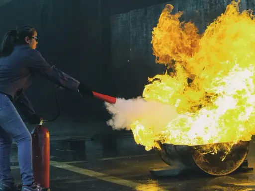 Övning i brandutbildning på jobbet. En person släcker en stor eld med en brandsläckare.