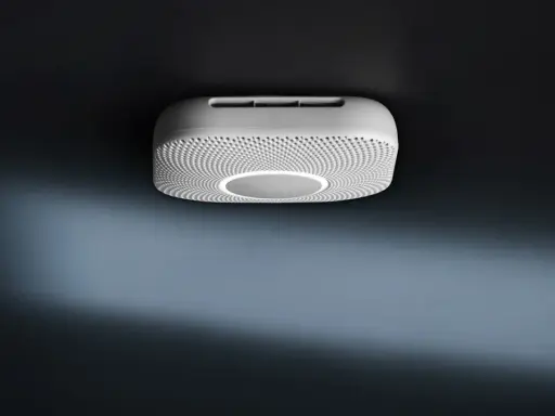 En vit Google Nest Protect-rökdetektor med en cirkulär ljusring monterad i taket.